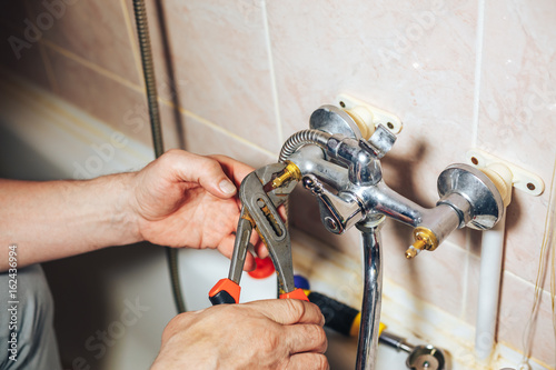 Fotoobraz na płótnie Mężczyzna naprawa i naprawianie przeciekającego starego faucet w łazience