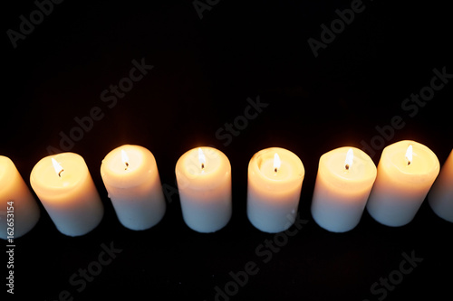 candles burning in darkness over black background