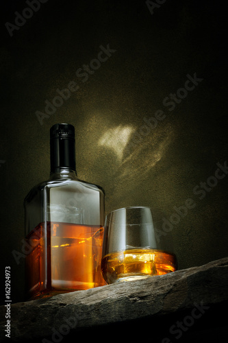 close up view of glass of  whiskey and a bottle aside