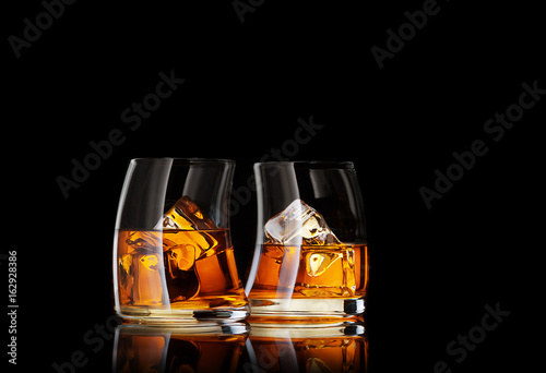 close up view of two glasses of  whiskey on black back
