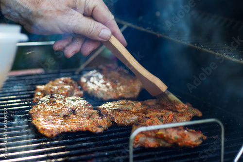Zdjęcie XXL Marynowanie mięsa podczas grillowania. Wieprzowina z grilla. Grill w ogrodzie. Ręka z pędzlem w ruchu.