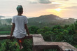The view from the back of a woman sitting on a high and watching sunset The view from the back of a woman sitting on a high and watching sunset