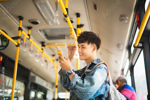 Zdjęcie XXL Azjatycki człowiek biorąc transport publiczny, stojąc wewnątrz autobusu.