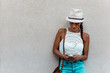 Fashion portrait of a sensual girl in a hat against the wall using phone Fashion portrait of a sensual girl in a hat against the wall using phone