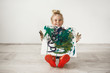 Indoor shot of blonde little girl with freckled face and hair bun looking at the camera, showing picture to her parents. Cute female child posing isolated at white wall. Indoor shot of blonde little girl with freckled face and hair bun looking at the camera, showing picture to her parents. Cute female child posing isolated at white wall.