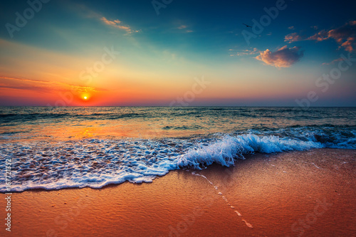 Beautiful sunrise over the sea and breaking ocean wave