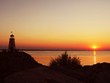 Beautiful sunset over the water, with silhouettes of a lighthouse, people and boats sailing Beautiful sunset over the water, with silhouettes of a lighthouse, people and boats sailing
