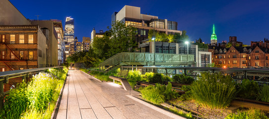 Panoramic view of the High Line promenade at twilight with city lights and illuminated skyscrapers. Chelsea, Manhattan, New York City