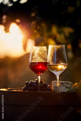 Two glasses of white and red wine with food at sunset