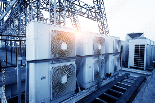 Zdjęcie XXL Klimatyzatory (HVAC) na dachu budynku przemysłowego z błękitne niebo i chmury w tle.
