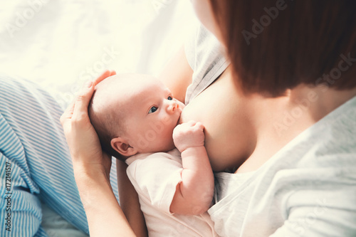 Mother breastfeeding newborn baby at home.