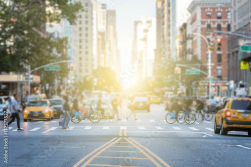 Zdjęcie XXL Ludzie przekraczający ruchliwe skrzyżowanie ruchu na 3rd Avenue i 10th Street na Manhattanie w Nowym Jorku z blaskiem światła słonecznego w tle