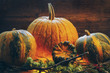 solid crust of pumpkin. on a wooden background. toned. grass and branches. halloween style solid crust of pumpkin. on a wooden background. toned. grass and branches. halloween style