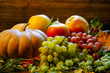 bright pumpkins, grapes and apples on branches and grass on a wooden background. halloween bright pumpkins, grapes and apples on branches and grass on a wooden background. halloween