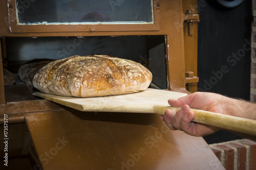 Plakat Baker zabranie chleba na jedzenie z drewnianą łopatą z tradycyjnego pieca piekarniczego