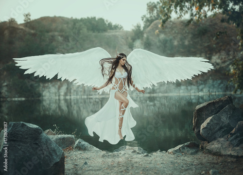 A beautiful white archangel descended from heaven. A girl in a sexy suit with huge white wings. Artistic Photography