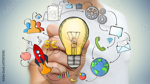 Businessman drawing a lightbulb with a pen with multimedia icons