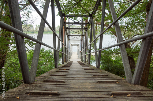 Fototapeta Wood and metal footbridge on the river in autumn