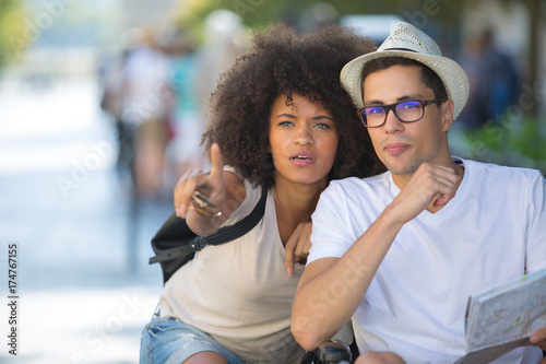 young couple using city map and pointing