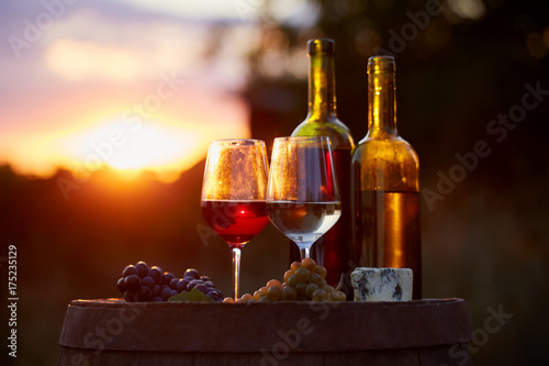 Two glasses of white and red wine with food at sunset