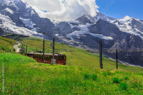 Zdjęcie XXL Słynny czerwony pociąg schodzący z Jungfraujoch Top of Europe do Kleine Scheidegg. Zdjęcie letnie - Kleine Scheidegg, Oberland Berneński, Szwajcaria