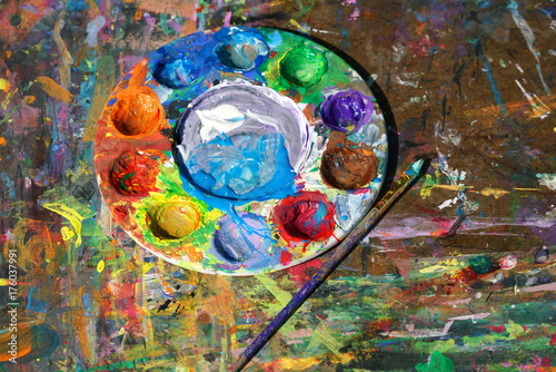 Round watercolor palette and paint brush on the board with color