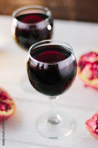 Organic pomegranate wine on white wooden table.