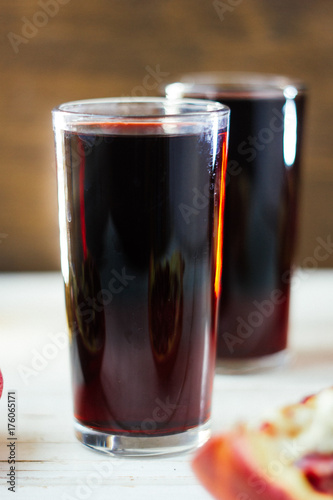 Nice pomegranate drink - fresh juice on white wooden surface.