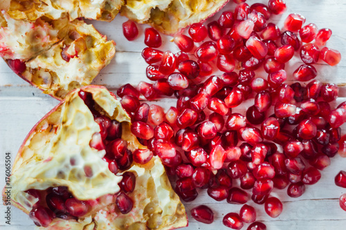 Pomegranate peel and seeds over white wooden background.