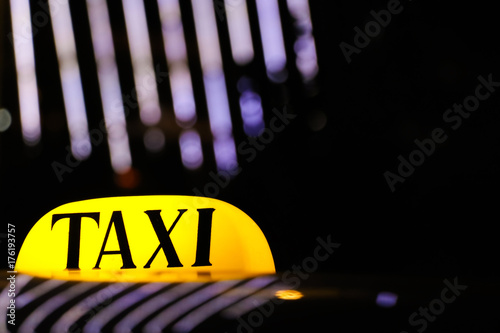 Zdjęcie XXL Rozjarzony taxi znak na dachu samochód w świetle świateł nocy miasto.