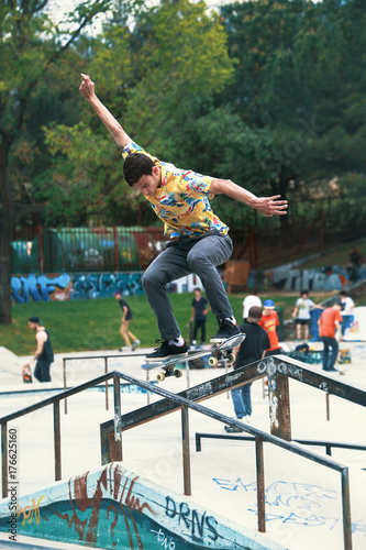 Zdjęcie XXL młody skateboarder trenuje na skate parku w poręczy / miejski skater robi sztuczki na rampie i railling in skatepark