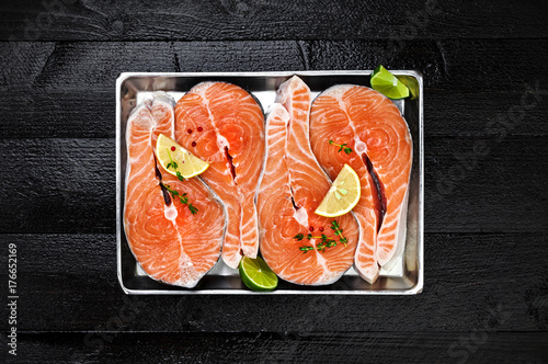Salmon steaks on metal tray on black wooden table top view