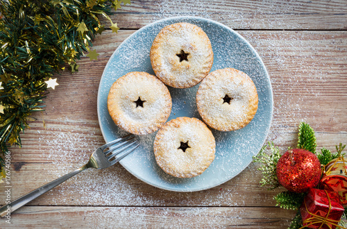 Blue plate with mince pies, fork and christmas decorations seen from above