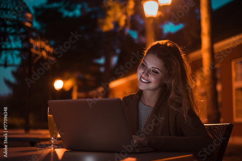Fotoobraz na płótnie Piękna dziewczyna pracuje przy nocą na laptopie, outdoors. Obraz o wysokiej czułości.