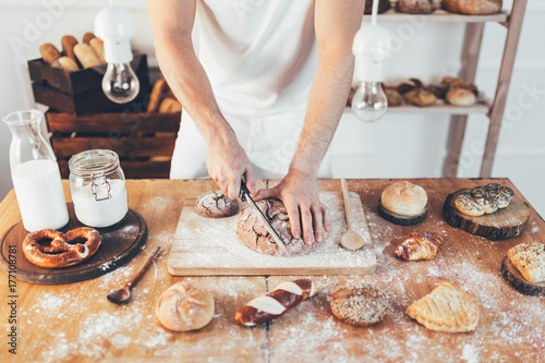 Fotoobraz na płótnie Baker z różnymi pysznymi świeżo upieczonymi chlebami i ciastami