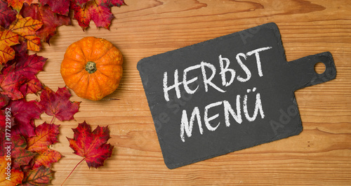 Herbstlaub mit Kürbis auf einem Holzbrett mit Schiefertafel - Herbstmenü