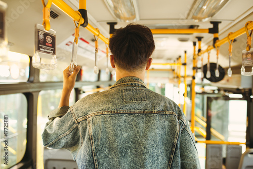 Zdjęcie XXL Azjatycki człowiek biorąc transport publiczny, stojąc wewnątrz autobusu.
