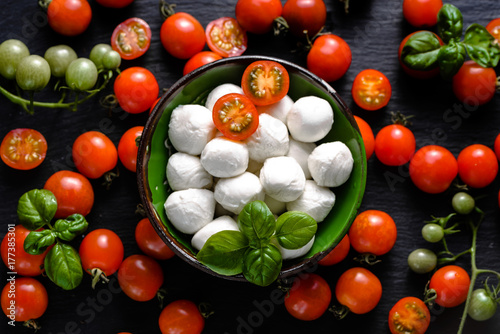 Plakat Włoskie jedzenie. Mozzarella, pomidory i bazylia na ciemnym łupku, nad głową