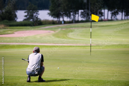 Zdjęcie XXL Mężczyzna planuje następnego uderzenie na golf zieleni żółtej flaga