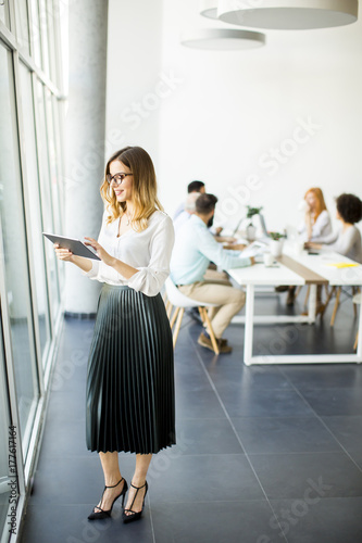 Elegant businesswoman standing in office with digital tablet