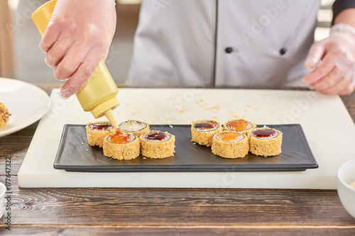 Plakat Szef kuchni nalewania sushi z sosem. Przygotowanie pysznego japońskiego sushi w profesjonalnej kuchni restauracji. Tradycyjne japońskie jedzenie.