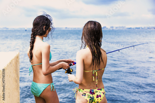 Fotoobraz na płótnie Dwie młode atrakcyjne dziewczyny w bikini łowią przynętę.