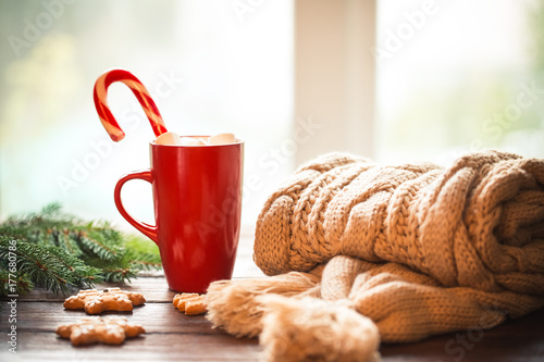 Zdjęcie XXL Bożenarodzeniowy miodownik, cukierek, kawa z marshmallows w czerwonej filiżance, trykotowy szalik, rożki i choinek gałąź na drewnianym stole na nadokiennym tle ,. Boże Narodzenie wakacje tło, zima przytulny dom