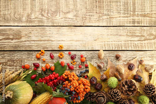 Autumn leafs with berries and cones on brown wooden table