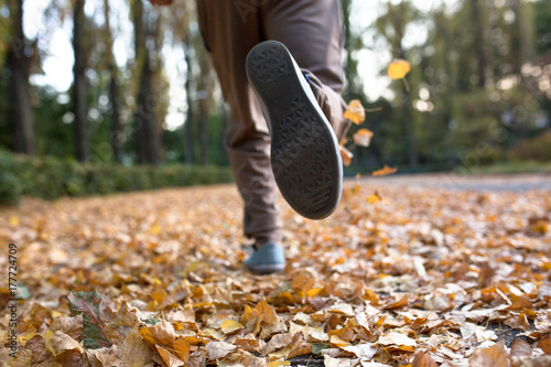 Zdjęcie XXL Jesieni jogger nogi zamykają w górę wizerunku. Męski bieg na wysuszonych lleaves w jesień parku.