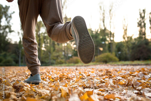 Zdjęcie XXL Zamyka w górę widoku mężczyzna bieg na wysuszonych jesień liściach. Zdrowy styl życia, mężczyzna jogging na zewnątrz.
