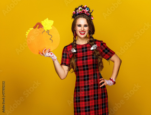happy woman in halloween costume showing pumpkin