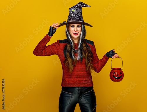 woman isolated on yellow background holding jack-o-lantern
