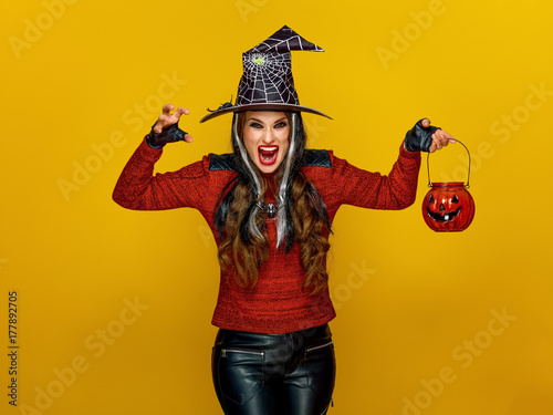 woman on yellow background with jack-o-lantern frightening