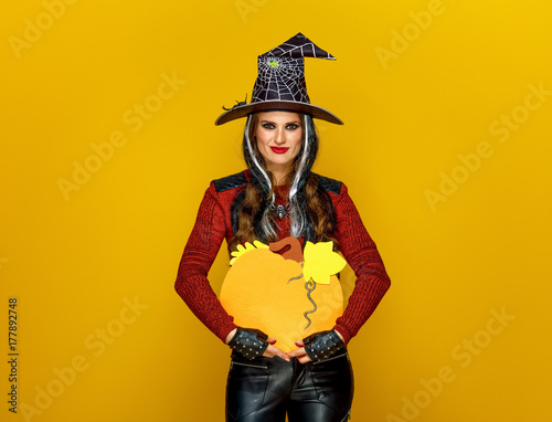 smiling modern woman isolated on yellow showing pumpkin